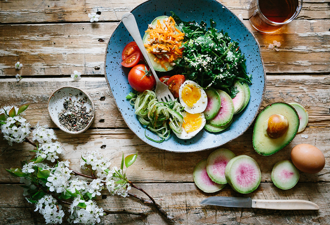 Salad On a wooden table is a salad arranged on a green plate, surrounded by cut fruits and vegetables.