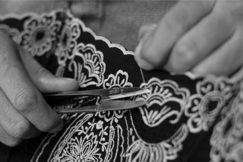 A black and white photo of someone cutting loose thread with scissors